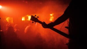 Silhouette eines Bassisten vor rot-orange beleuchteter Konzertbühne