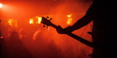 Silhouette eines Bassisten vor rot-orange beleuchteter Konzertbühne