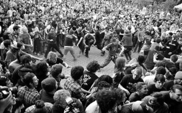 Schwarz-weiße Aufnahme eines dicht gedrängten Moshpits mit tanzenden Fans