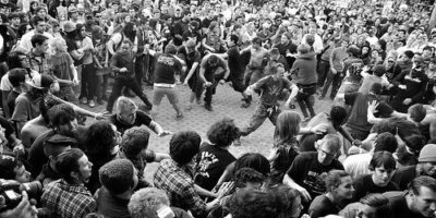 Schwarz-weiße Aufnahme eines dicht gedrängten Moshpits mit tanzenden Fans