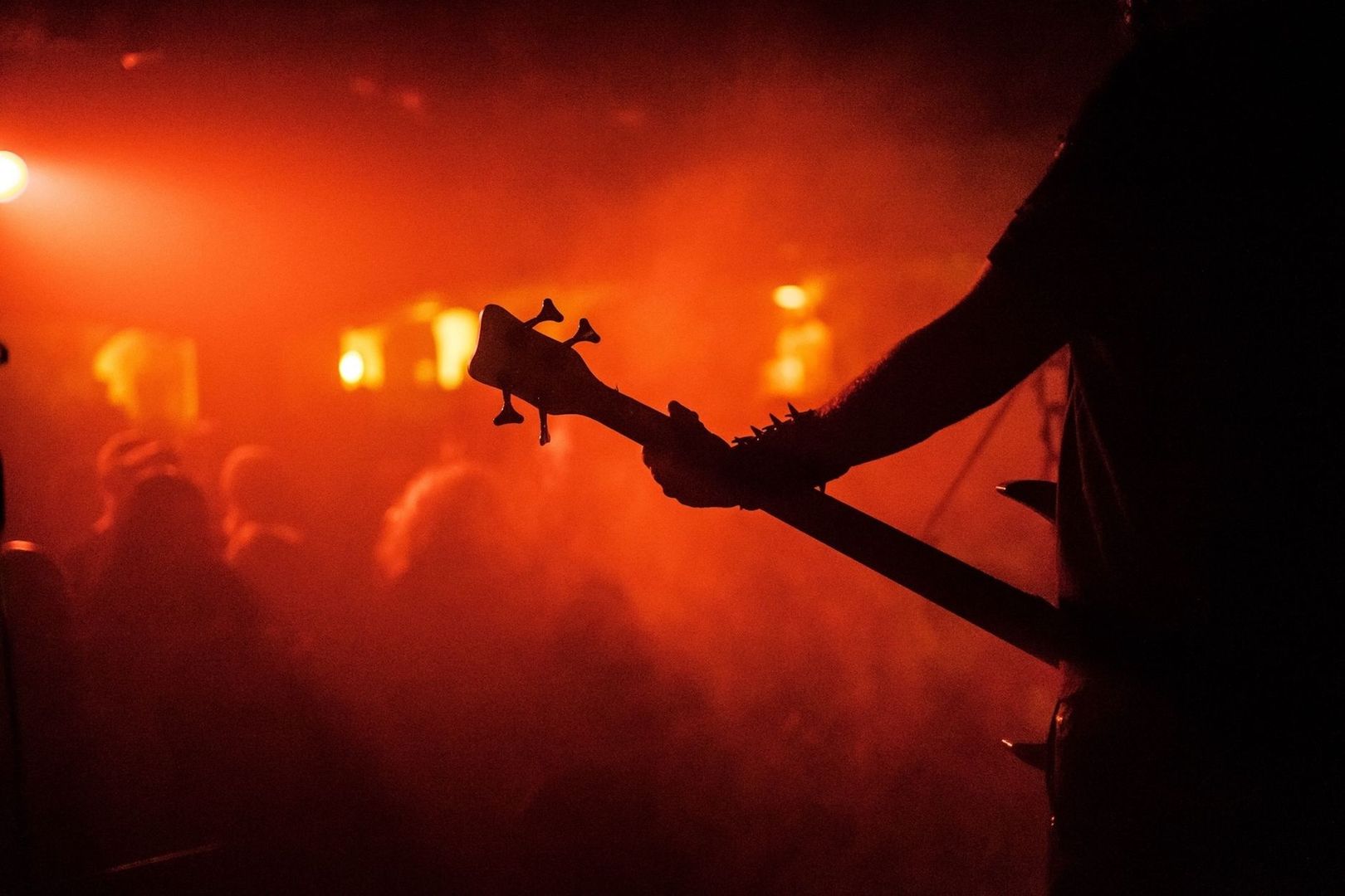Silhouette eines Metal-Gitarristen vor rotem Licht und Konzertpublikum